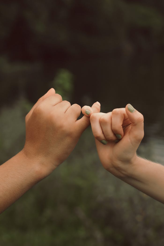 Close-up of two hands making a pinky swear, symbolizing trust and friendship.